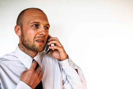man-met-overhemd-die-belt-op-smartphone-online-versie